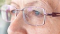 Sad senior woman`s eyes with glasses macro photography. Close-up of wrinkles on the mature skin of the face. The concept of visio