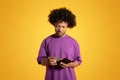 Sad serious mature black curly man in purple t-shirt thinks, counting money dollars in wallet Royalty Free Stock Photo