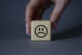 Sad smile symbol. Sad smile on wooden cube. Businessman hand. Beautiful grey background. Business and Sad smile concept. Copy