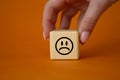 Sad smile symbol. Sad smile on wooden cube. Businessman hand. Beautiful orange background. Business and Sad smile concept. Copy