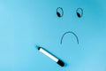 A sad smiley is drawn with a marker on a blue background. Free space for text