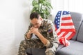 Sad soldier in uniform covering his mouth while sitting on a sofa Royalty Free Stock Photo