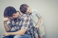 Sad son hugging his dad near wall Royalty Free Stock Photo