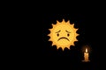 A sad sun and a lonely candle in the dark. Space for text. Royalty Free Stock Photo