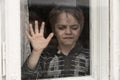 A sad, tearful boy leaned his hand against the window. Farewell (concept: orphan, war)