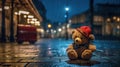 A sad teddy bear in the night city sitting on the street. The little bear is alone in the dark rainy night, abandoned.