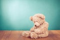 Sad Teddy Bear toy sitting alone on wooden floor in front mint blue background. Vintage style filtered photo Royalty Free Stock Photo