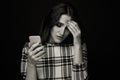 Sad teen being victim of cyber bullying online sitting on a couch in the living room at Royalty Free Stock Photo