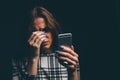 Sad teen being victim of cyber bullying online sitting on a couch in the living room at Royalty Free Stock Photo