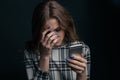 Sad teen being victim of cyber bullying online sitting on a couch in the living room at Royalty Free Stock Photo