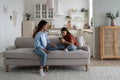 Sad teenage girl sitting with mother on sofa holding mobile phone, being bullied on social media Royalty Free Stock Photo