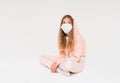 Sad teen girl in pink hoodie in face mask girl in closed position isolated on the white background