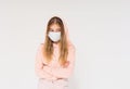 Sad teen girl in pink hoodie in face mask girl in a closed position on white background