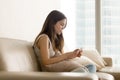 Sad teen girl using phone while sitting on sofa Royalty Free Stock Photo