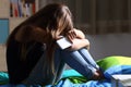 Sad teen with a phone in her bedroom