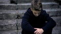 Sad teen sitting on old cracked steps, feeling grief and sorrow, parents loss