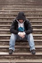 Sad teenage boy with hood sitting on stairs Royalty Free Stock Photo
