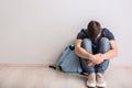 Sad teenage boy sitting on floor indoors. Bullying at school Royalty Free Stock Photo