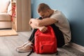 Sad teenage boy sitting near color wall indoors. Bullying at school Royalty Free Stock Photo