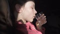 Sad teenage girl drinks water from an ailment in the cabin of plane while traveling