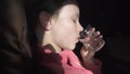 Sad teenage girl drinks water from an ailment in the cabin of plane while traveling