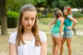 Sad teenage girl rejected by other teenage girls in park