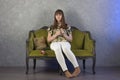 Sad teenage girl sits on green sofa. On gray background. Studio. Royalty Free Stock Photo