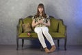 Sad teenage girl sits on green sofa. On gray background. Studio. Royalty Free Stock Photo