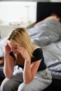 Sad Teenage Girl Sitting In Bedroom Whilst Boyfriend Sleeps Royalty Free Stock Photo