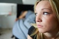 Sad Teenage Girl Sitting In Bedroom Whilst Boyfriend Sleeps Royalty Free Stock Photo