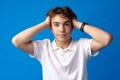 Sad teenager boy failed, touching face against blue background Royalty Free Stock Photo