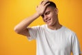 Sad teenager boy failed, touching face against yellow background Royalty Free Stock Photo