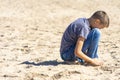 Sad teenager boy sitting and thinking on empty beach alone Royalty Free Stock Photo