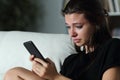 Sad teenager checking phone cyber bullying messages Royalty Free Stock Photo