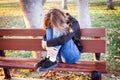 Sad teenager girl sitting on the bench in autumn park. Crying young girl in depression Royalty Free Stock Photo