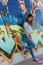 Sad teenager leaning against a graffiti wall