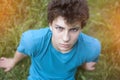 A sad teenager sits on the grass and looks upstairs. He suffers from pimples and acne on his face Royalty Free Stock Photo