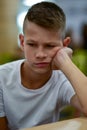 Sad teenager sitting on a chair in front of the table Royalty Free Stock Photo