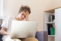 Sad Teenager working on laptop on the couch at home. Upset Boy makes homework with a computer. Distance, online education Royalty Free Stock Photo