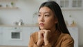 Sad thoughtful Asian chinese korean single woman pensive looking away thinking of grief problems sit lonely in domestic Royalty Free Stock Photo