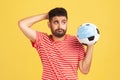 Sad thoughtful man in red t-shirt holding soccer ball in protective mask, symbol of football competition during covid-19 virus,