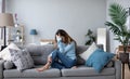 Sad thoughtful worried young woman sit on sofa, psychological problem