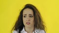 Sad thoughtful young beautiful woman standing in Studio with yellow Background.