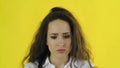 Sad thoughtful young beautiful woman standing in Studio with yellow Background.