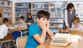 Tired boy reading textbooks in school library Royalty Free Stock Photo