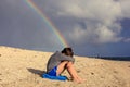 Sad tired boy and rainbow on tropical ocean beach. Royalty Free Stock Photo
