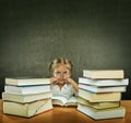 Sad, tired, busy little girl with big eyes, wearing glasses sitting in the pew next to him many, many books Royalty Free Stock Photo