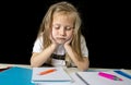 Sad tired cute blond junior schoolgirl in stress working doing homework bored overwhelmed Royalty Free Stock Photo