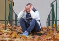 Sad tired-looking man, middle-aged, depressed, sitting on the steps Royalty Free Stock Photo