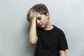 A sad tired schoolboy stands against a gray wall. Handsome guy in a black t-shirt. Difficulties in learning and stress Royalty Free Stock Photo